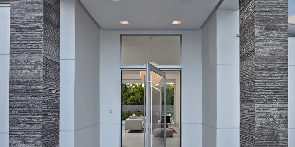 The entryway of this home sets the tone for its modern sophistication, featuring a stunning pivot door that exemplifies contemporary elegance. This thoughtful design choice seamlessly integrates the exterior's sleek facade with the interior's refined ambiance. The use of neutral tones and textural elements enhances the minimalist aesthetic, while strategic lighting provides both functionality and dramatic effect, ensuring a welcoming and stylish first impression.