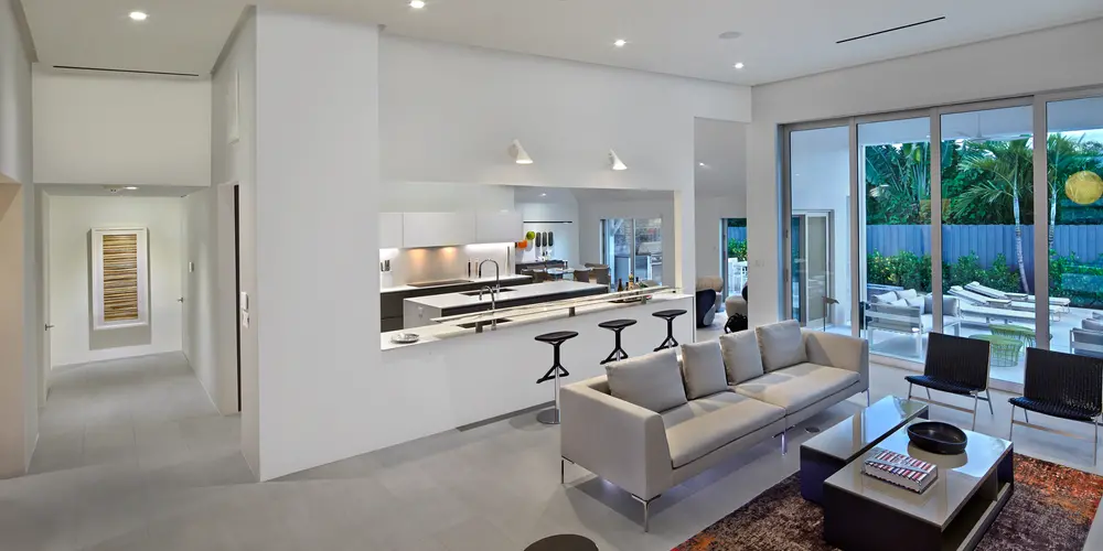 This angle of the open-concept living and kitchen area underscores the home’s cohesive design and attention to detail. The seamless integration of living spaces ensures functionality and flow, with the kitchen acting as a central hub that connects to the rest of the home. Modern furnishings and minimalistic decor contribute to an inviting and sophisticated atmosphere, while the strategic placement of lighting enhances the room's elegance and usability.