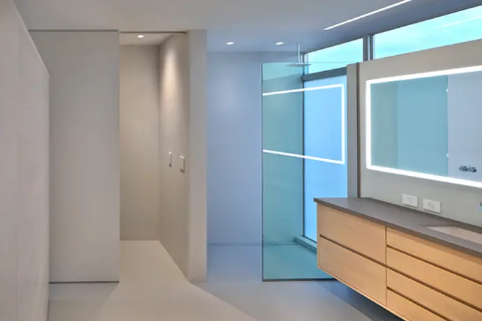 This bathroom space combines high-tech elegance with clean architectural lines. A striking use of frosted glass panels and integrated lighting creates a contemporary and serene ambiance. The wooden vanity adds warmth and sophistication, ensuring the space feels inviting and luxurious.