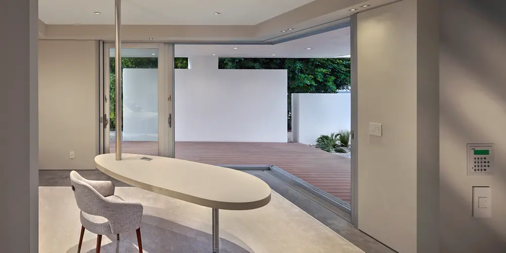 The interior office space is defined by its open layout and abundant natural light. Glass sliding doors enhance flexibility and integration with the outdoor environment. The sleek design and minimalistic furnishings create an atmosphere conducive to creativity and focus.