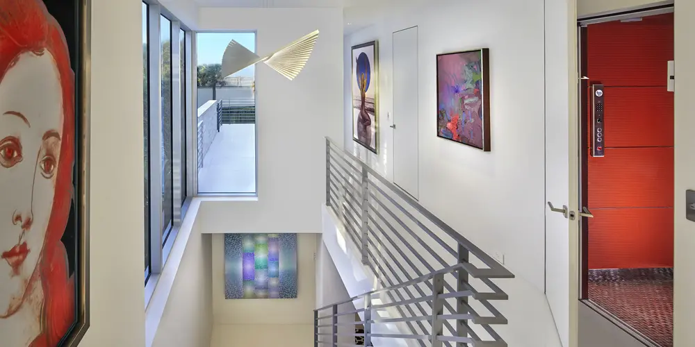 This staircase area emphasizes modern design with sleek railings and strategic art placements, creating a dynamic blend of aesthetics and functionality in the vertical space.