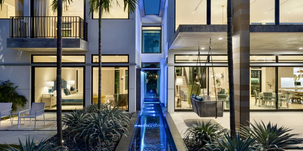 A captivating water feature runs alongside the home, accentuated by night lighting. The reflective waters complement the modern glass façade, adding a tranquil touch to the exterior.