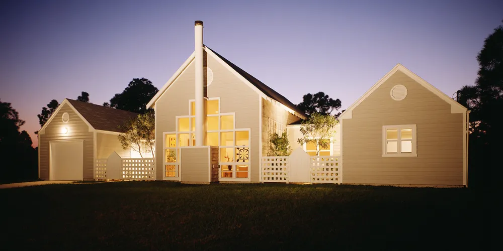 This home's exterior architecture blends classic design with modern touches. Featuring symmetrical peaked roofs and creative geometric window patterns, it combines traditional forms with thoughtful design innovation. The facade's subtle details, such as the unique chimney and entryway, enhance its functional and aesthetic appeal, harmonizing with the natural surroundings.

