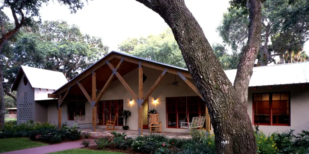 The front view during the daytime highlights the harmonious blend of nature and architecture. The rich-hued wooden accents and open structure provide a welcoming entrance, emphasizing the modern revamp while maintaining a sense of organic warmth.