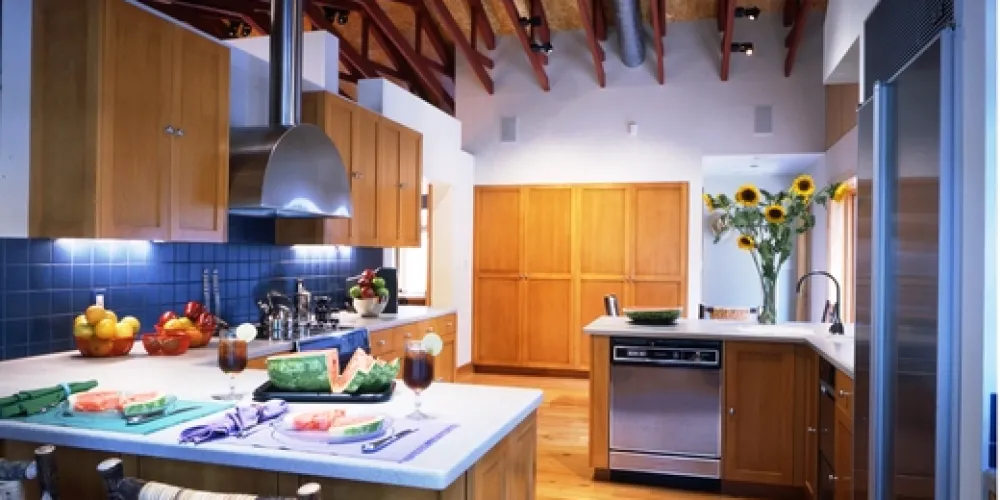 Inside, the kitchen exemplifies a modern interpretation of rustic elegance, featuring exposed roof trusses that add to its industrial appeal. Natural wood finishes, sleek appliances, and contemporary design come together in a vibrant yet cozy setting, embracing functional beauty with an airy, open plan.