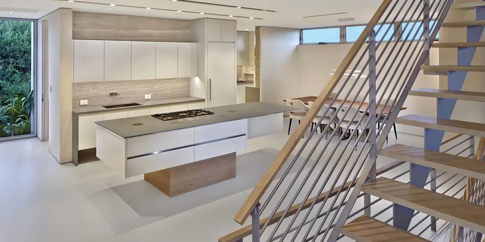 The kitchen reflects modern functionality with sleek appliances, minimalist cabinetry, and a neutral palette. The open-plan layout connects with the dining area, blending materials like wood and metal for a harmonious and practical living space.
