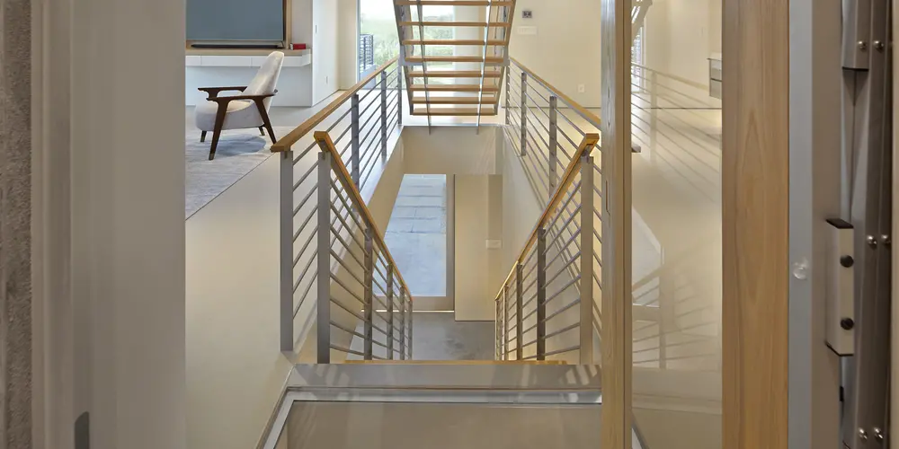 The staircase creates a visual connection between floors with its open concept and elegant materials.