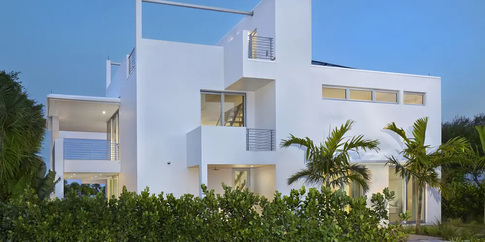 The rear view of the home reinforces its modern aesthetic with layers of geometric planes and large windows. Surrounding greenery offers a natural backdrop, creating a balanced indoor-outdoor relationship.
